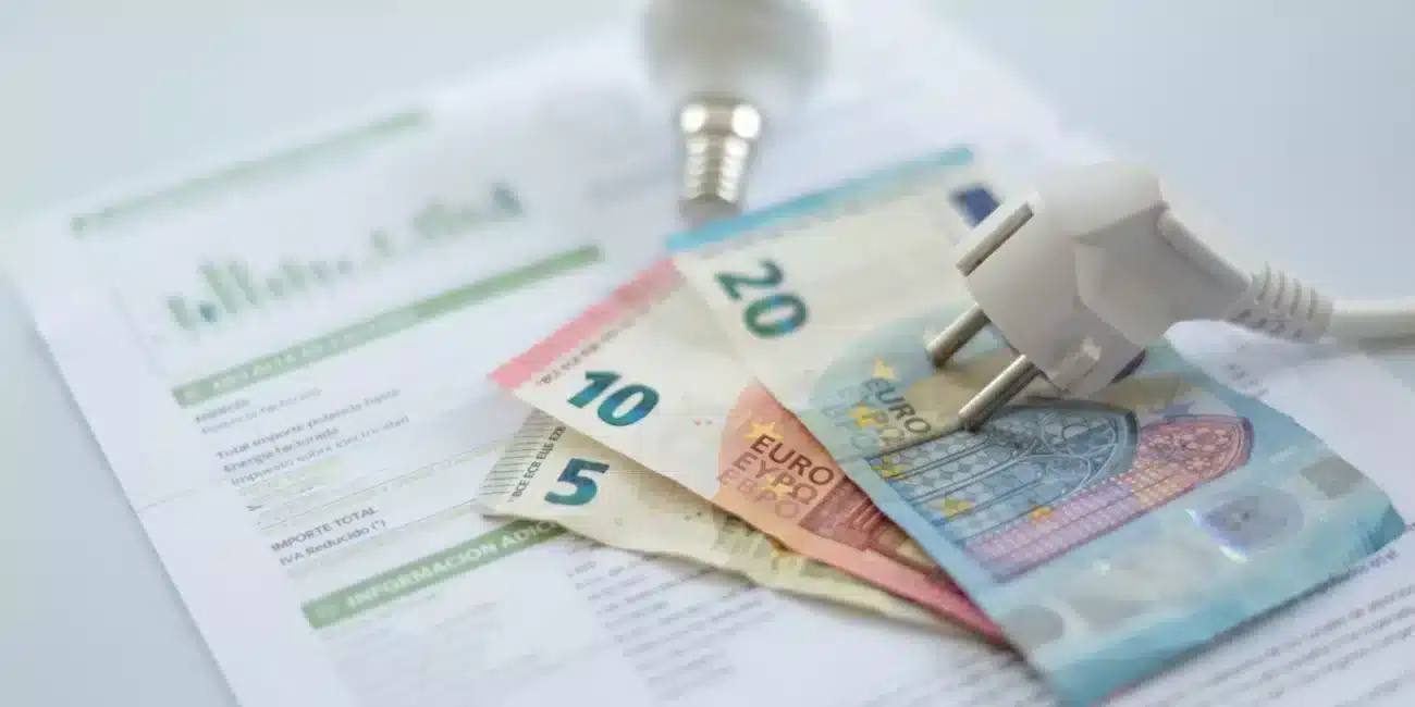 Factura de electricidad cara con billetes de euro y bombilla, representando el ahorro en la tarifa de luz